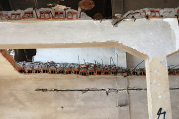 Fragmenty muru i cegieł z rozwalonej fabryki widoczne wiszące druty.