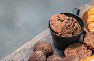 Closeup of assort chocolate chip cookie and bakery jar on wooden table with copy space.