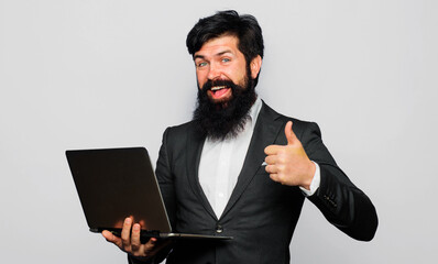 Happy bearded man with laptop computer showing thumbs up. Office, business, technology, internet.