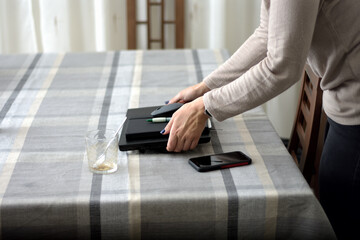 A businesswoman and entrepreneur picking up her laptop, laptop mouse, pen and diary from the table when she finishes working from home. selective focus