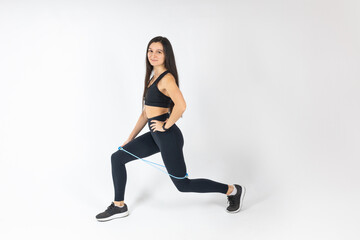 Sportswoman exercising with resistance band on white background. Attractive brunette woman in fashionable sportswear exercising. Healthy lifestyle, sport concept, Full length view