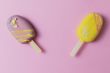 2 popsicle cake pink and yellow glaze and colored sprinkles on a pink background. Space for text.