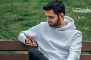 young man on bench with mobile phone