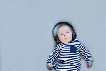 cute baby boy on gray blanket background with headphones. little kid