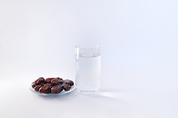 Dry pitted dates fruits and glass of water on white background. Ramadan fasting concept....