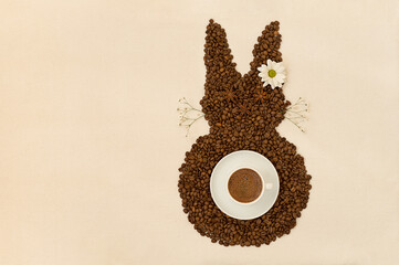 Creative top view flat lay of Easter bunny shape made of coffee roasted beans and cup of espresso...