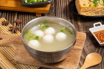 cod ball soup in a steel bowl isolated on wooden board side view on table taiwan food