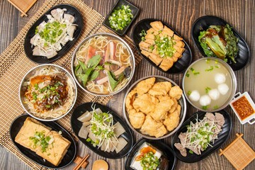 Assorted taiwan soup and noodles, pig skin, squid soup slabs, cod ball soup, blanched vegetables, raw squid soup noodles, dried follower, powder sausage, oily tofu, chilli sauce top view on table