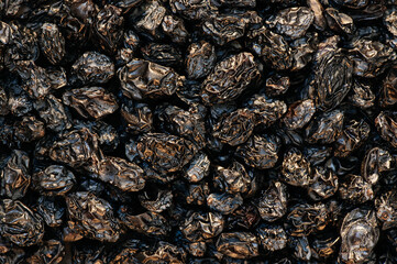 Close up textured background of black dried grape raisins in pile. Healthy food concept. 