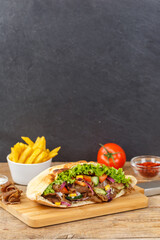 Döner Kebab Doner Kebap slice fast food in flatbread with French Fries on a wooden board portrait...