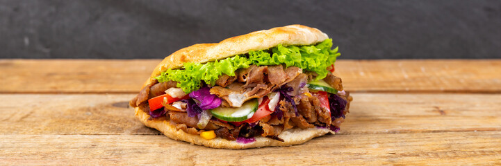 Döner Kebab Doner Kebap fast food in flatbread on a wooden board panorama - 495305674