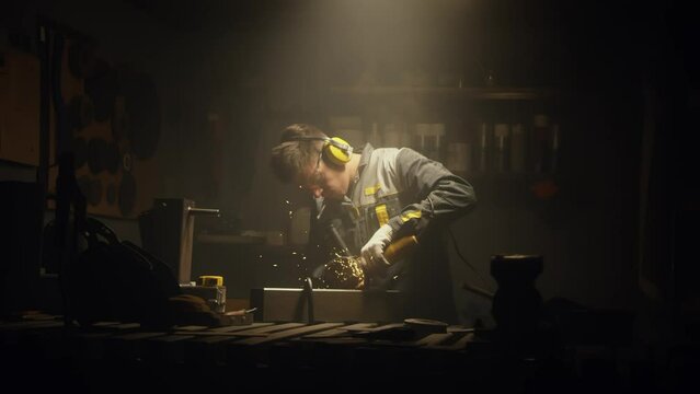 A man works with a circular saw. Worker grinder grinds metal in workshop. Sparks fly from hot metal. The man worked hard on the steel. Close-up slow motion in the garage. 4K video. Shot on RED