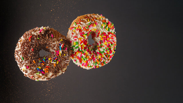 Two colorful donuts in frozen flight on a gray background. There are no people in the photo. There is free space to insert. Confectionery, shop, culinary blog.