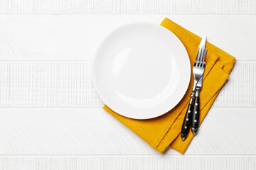 Empty plate and silverware on wooden table