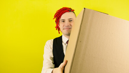 Young man in white shirt, vest and tie with cardboard box on yellow background in studio. Male courier with package. Concept of delivery and transportation.