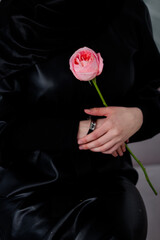 Muslim woman in hijab with a rose in her hands. A woman in a black hijab. Tenderness. close plan.