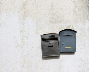 Two metal mailboxes hang on a light, dirty wall. Old mailboxes. 