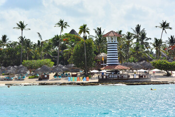 Bayahibe, la Romana, Dominican Republic - White motorboat and striped lighthouse on the beach by the sea