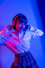Fototapeta na wymiar High Fashion model woman in colorful bright neon blue and purple lights posing in studio. Portrait of beautiful woman with trendy glowing make-up. Art design vivid style 