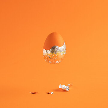 Creative Easter egg with foil against an orange background. Creative holiday or futuristic concept.