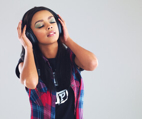 Tunes to make her swoon. Studio shot of a young woman listening to music through her headphones.