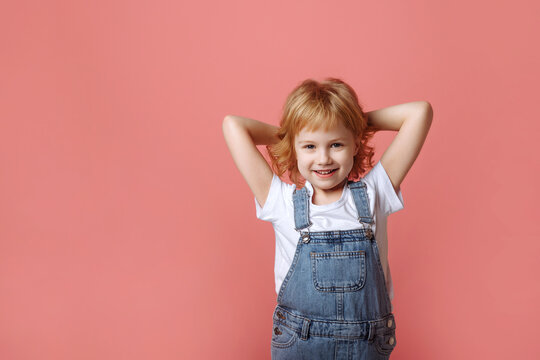 Cheerful little girl jumping on a pink background.