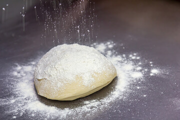 The cook rolls the dough into a thin sheet.