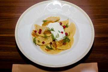 Traditional Ukrainian dishes - dumplings with sour cream, fried onions and cranberries are on a plate