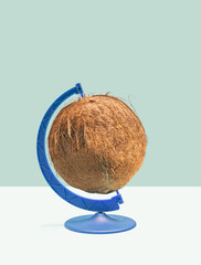 Minimal raw plant based concept. One organic coconut set in a rotating blue stand. Pastel blue and beige background.