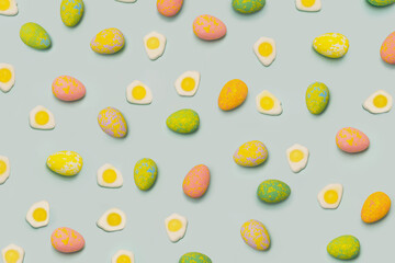 Fototapeta na wymiar Lovely Easter minimal concept. Optimistic flat lay pattern arrangements made of colorful painted egg and fried eggs with green background.
