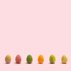 Optimistic minimal Easter concept.  Arrangement of six colorful painted eggs in line . Pastel pink background.