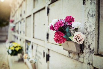 Flowers for the deceased. Shot of a row of graves situated next to each other inside of a graveyard outside during the day.