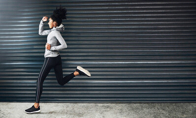 Just do your best and forget the rest. Shot of a sporty young woman running against a grey background.
