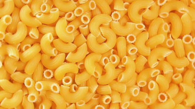 Uncooked Chifferi Rigati Pasta - Top View, Close-Up. Fat and Unhealthy Food. Classic Dry Macaroni, Rotating Background. Italian Culture and Cuisine. Raw Golden Pasta Texture - Right Rotation