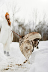 Happy young woman with a purebred dog for a walk in winter nature winter holidays