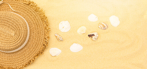 Fototapeta na wymiar Straw hat on the sand with shells