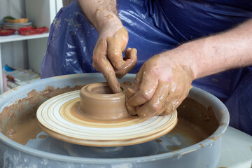 senior pottery man hands sculping from clay on pottery wheel pot in workshop. Concept of ceramic...