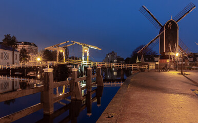 Fototapeta premium An old wooden mill on the banks of a canal in Leiden at dawn.
