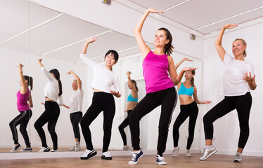 Fototapeta na wymiar Cheerful different ages women learning swing steps at dance class. High quality photo