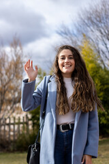 vertical portrait of a smiling young caucasian woman waving. Video call screen