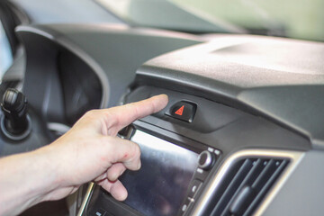 Closeup of man's hand pressing emergency stop button in car. using human hand to push the hazard...