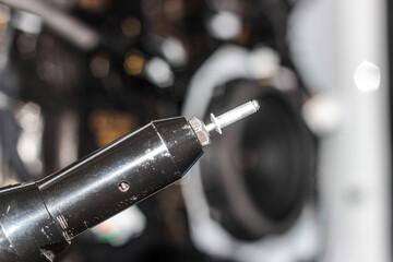 Rivet gun, applicator and rivets. Installing the speaker in the car. An auto mechanic installs a car speaker from the door using a rivet. The process of working with a rivet close-up.