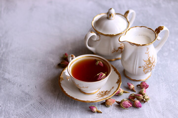 Tea with roses close up photo. Herbal tea in a small white ceramic cup on a table. Light grey background with copy space. 