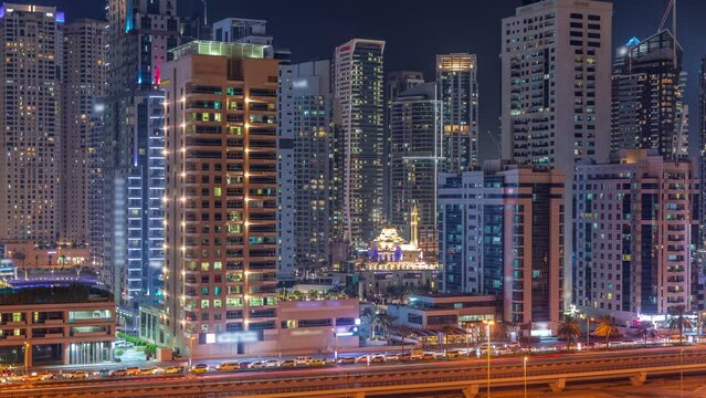Dubai Marina skyline with Mohammad Bin Ahmed Al Mulla mosque aerial timelapse at night.