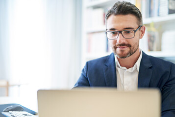 Getting things done through technology. Shot of a mature businessman working at his computer in an...