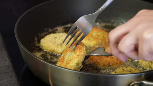 Close up shot of cheese snacks fried rotating in a frying pan. Preparing healthy tasty breakfast at home. 4k video
