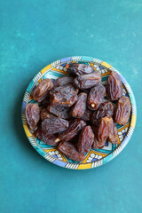 Dried dates on a blue ceramic plate. Close up photo of sweet dates on a table. healthy eating concept. 