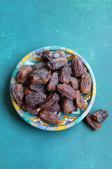 Dried dates on a blue ceramic plate. Close up photo of sweet dates on a table. healthy eating concept. 