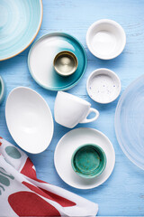 Dishes for serving and eating meals on a wooden background, top view. Modern ceramic and glass crockery, trendy tableware.