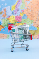 Shopping trolley is loaded with ruble banknotes on the background of the political map of Europe....